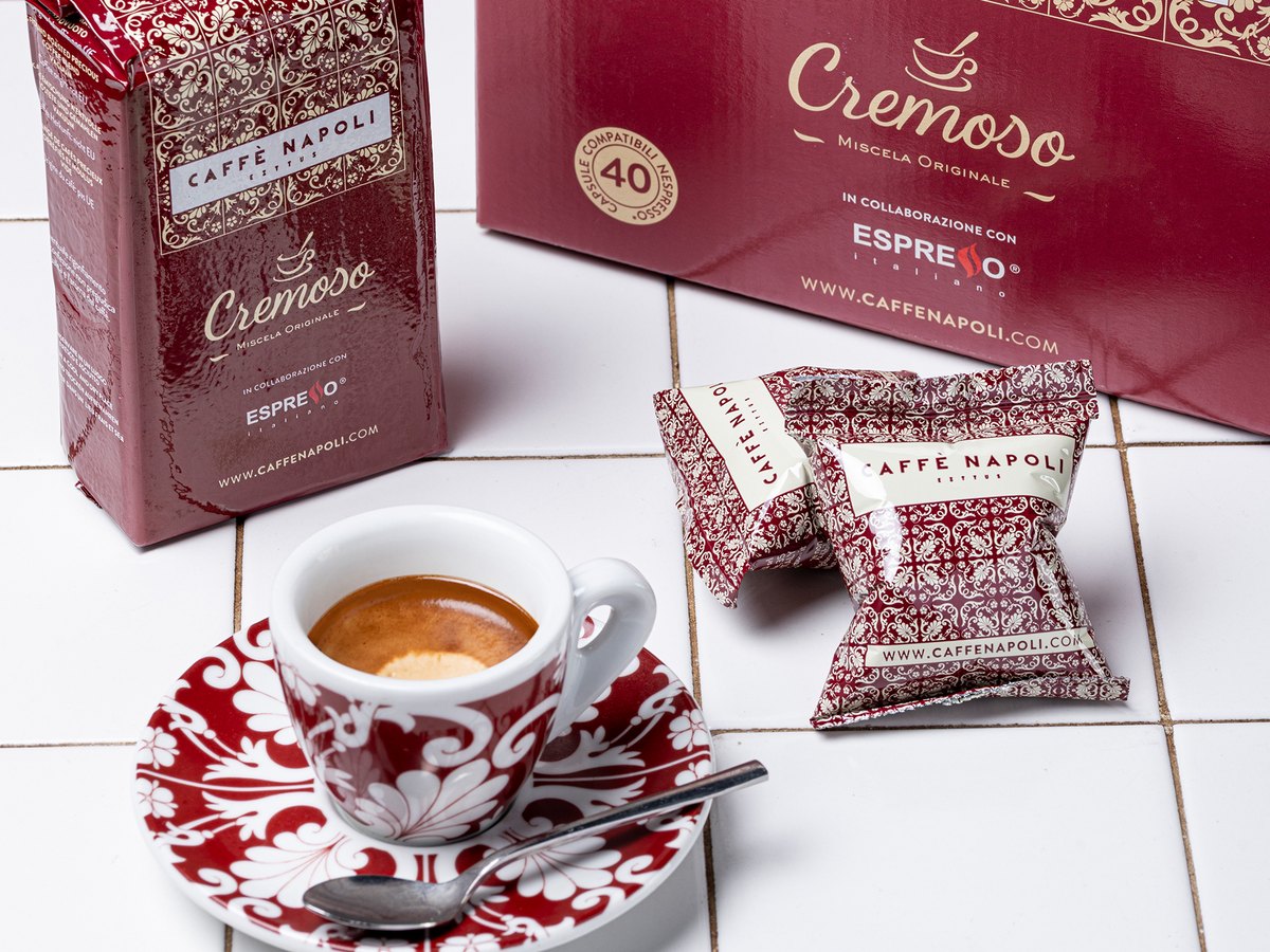 Astuccio, busta e cialde della linea Caffè Cremoso accanto a un espresso