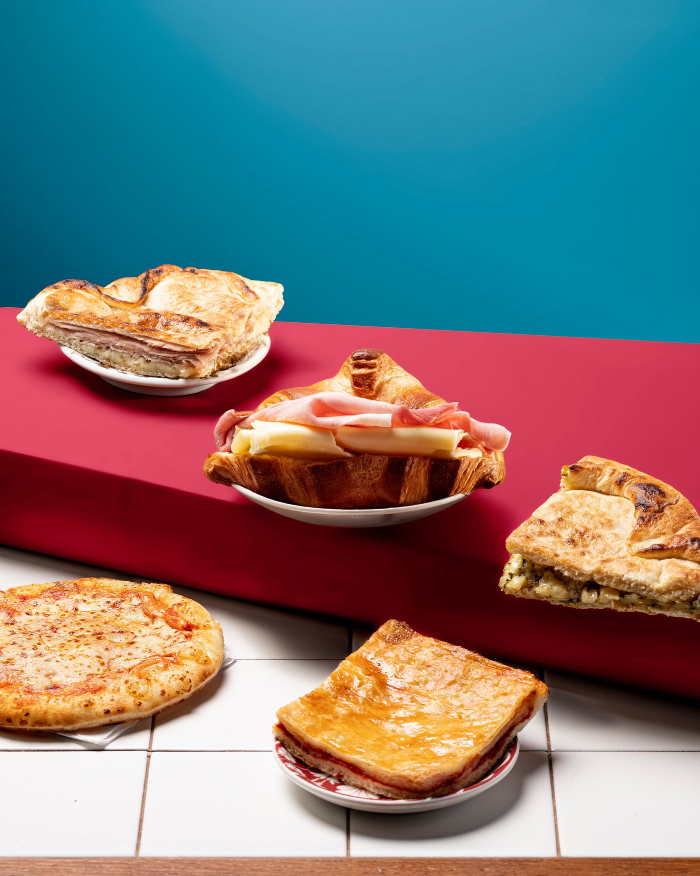 Cornetto salato, pizzetta, parigina e focacce rustiche su un banco rosso