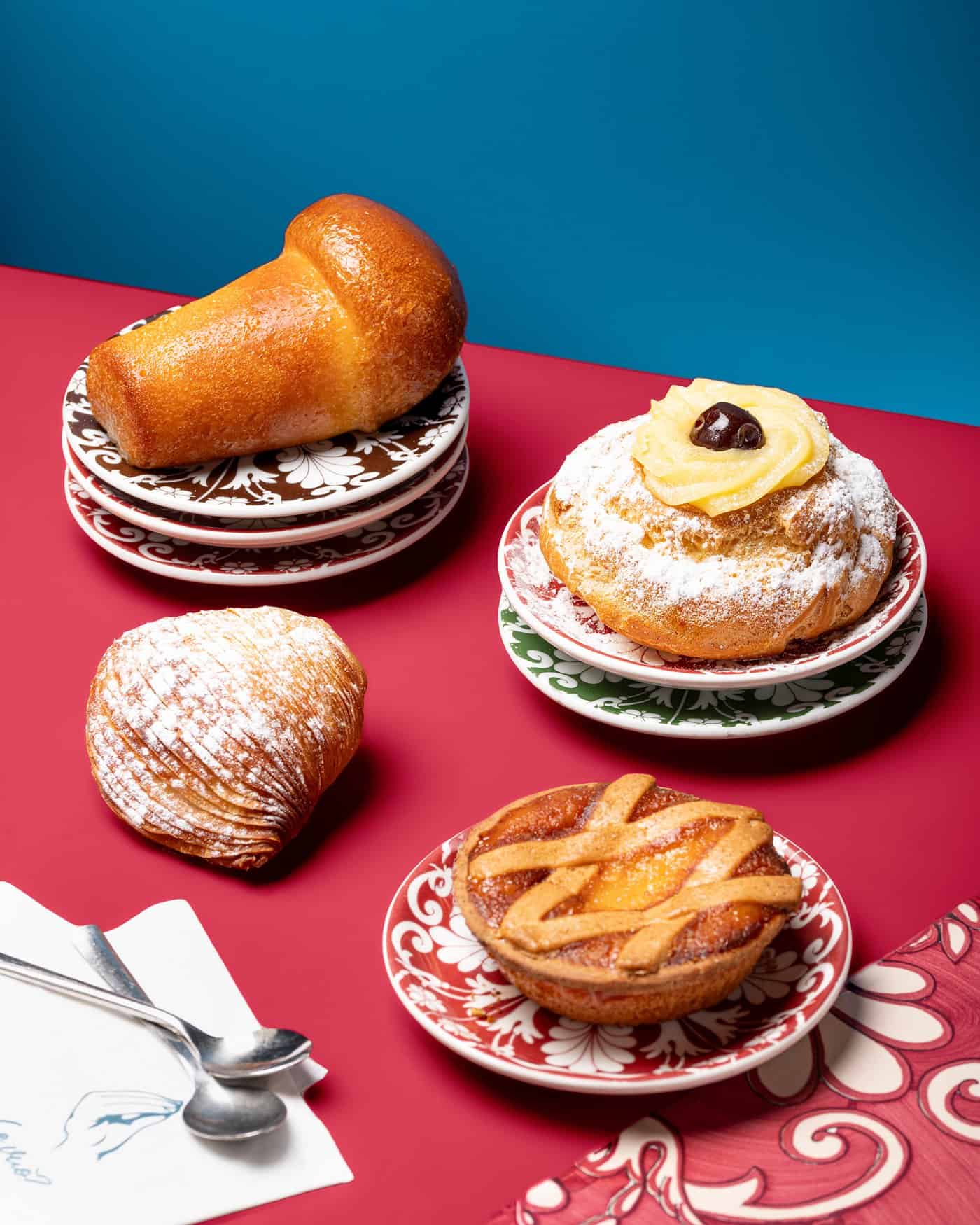 Babà, sfogliatella, pastiera e zeppola su piatti di maiolica napoletana